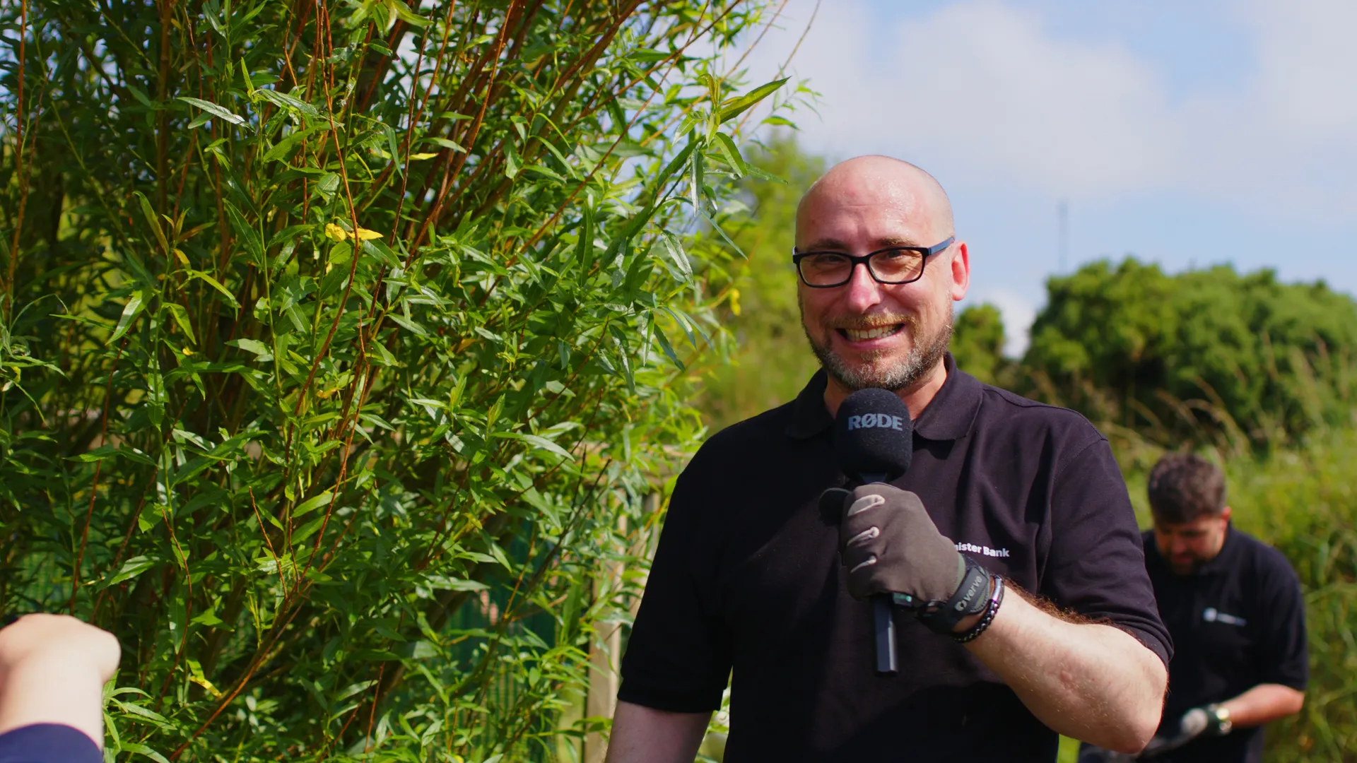 Conister Bank volunteers working among tall grass and vegetation during the bee safe garden project at The Children's Centre, Isle of Man, filmed by DotPerformance